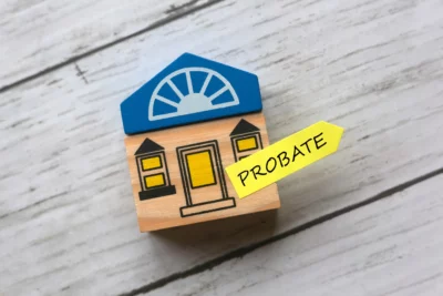 Small wooden house block with a yellow label that says probate on a light wooden surface.