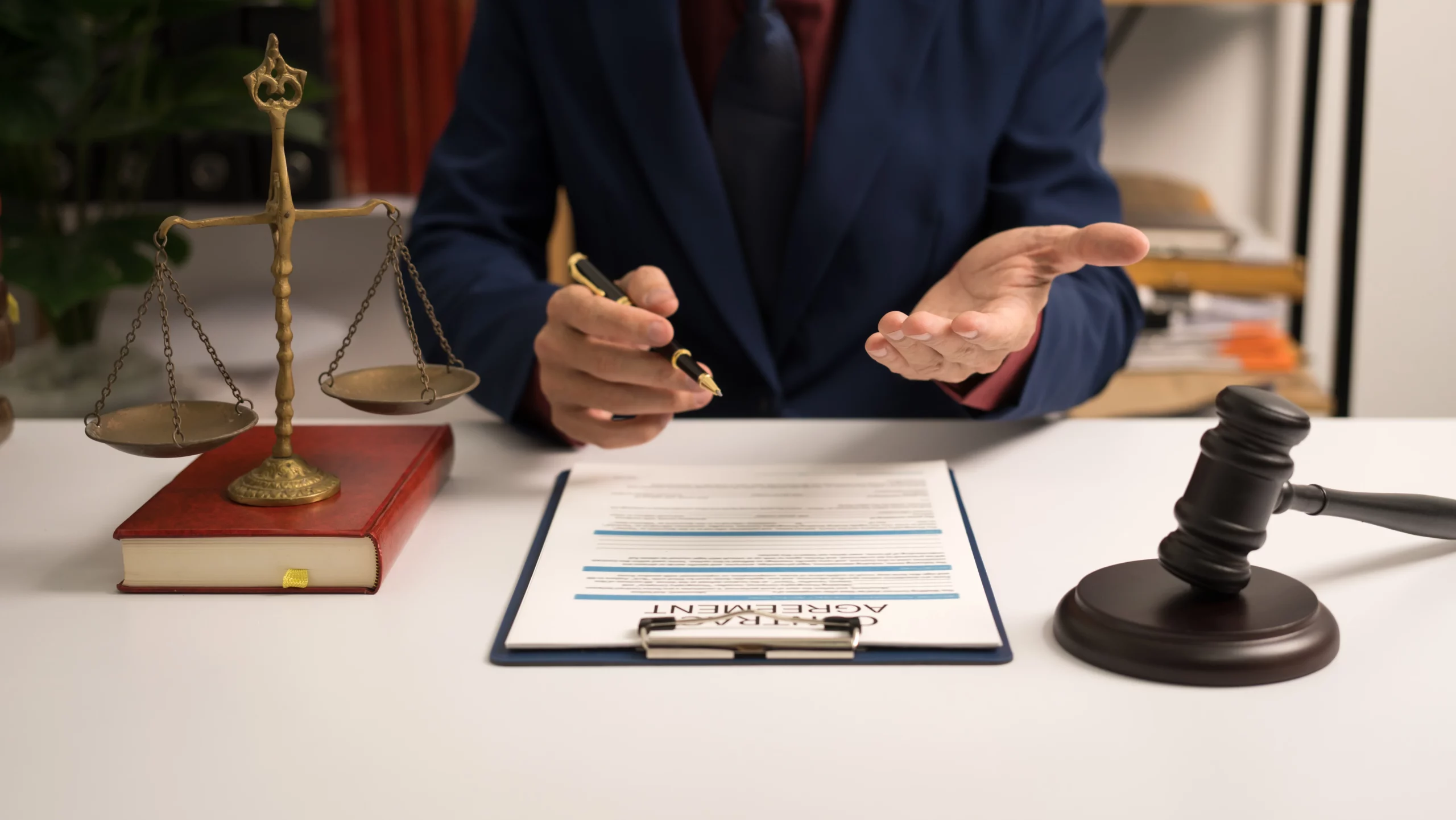 Business credit application on a table with pen, nearby calculator, and a suited person at a desk holding a pen and pointing at an “Agreement” document beside legal symbols—conveying the legal and financial steps involved in establishing a power of attorney in California.