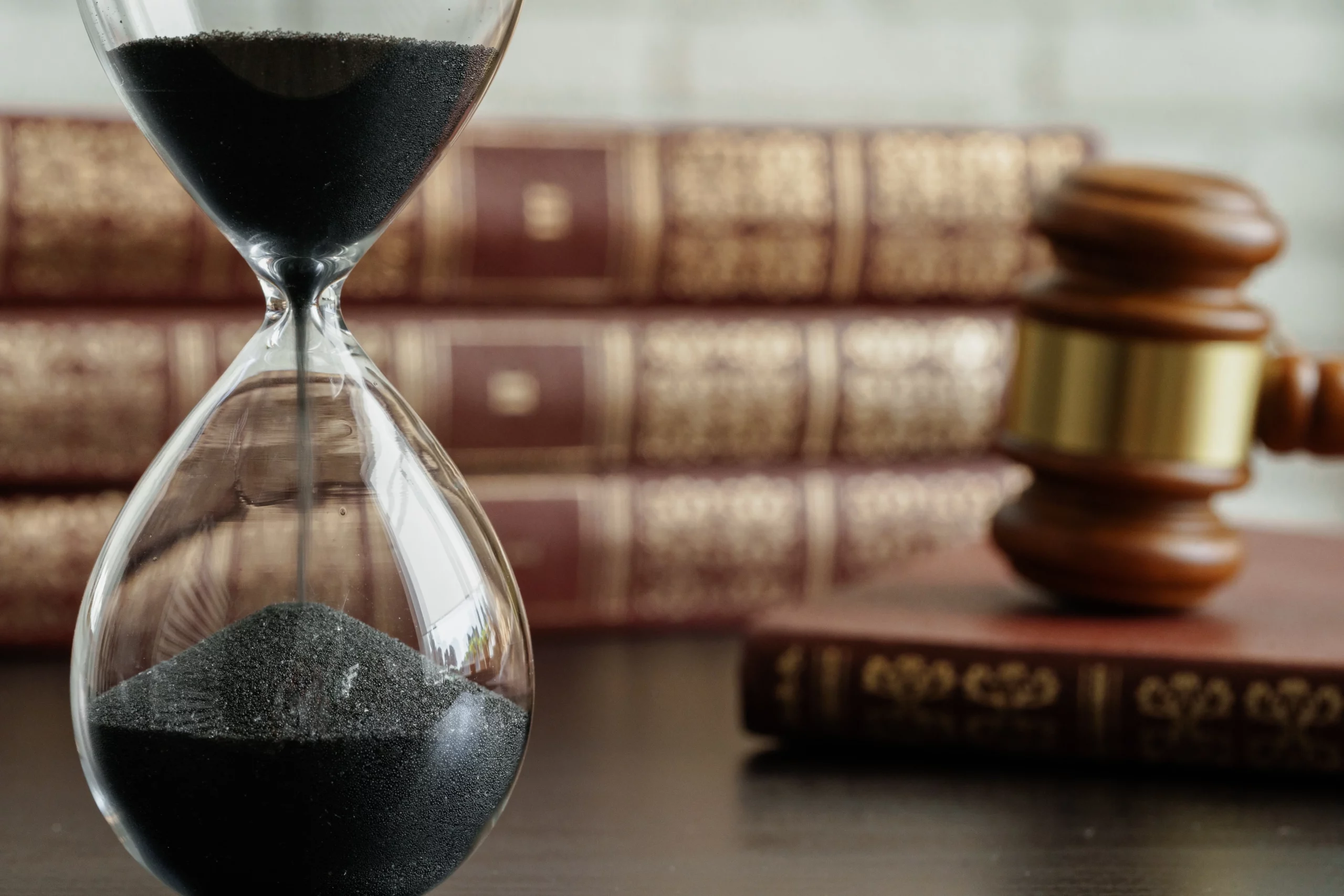 Hourglass with black sand beside a gavel and legal books, symbolizing the 120‑day time limit for contesting a trust in California.