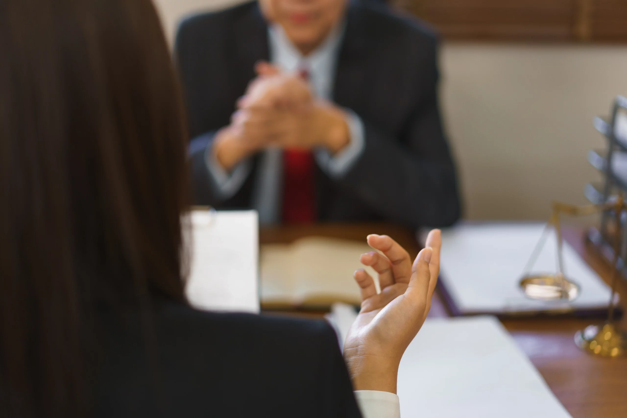 Woman gesturing at man in suit across a desk with legal scales, illustrating serious discussion of trustee and beneficiary rights in California trust law.