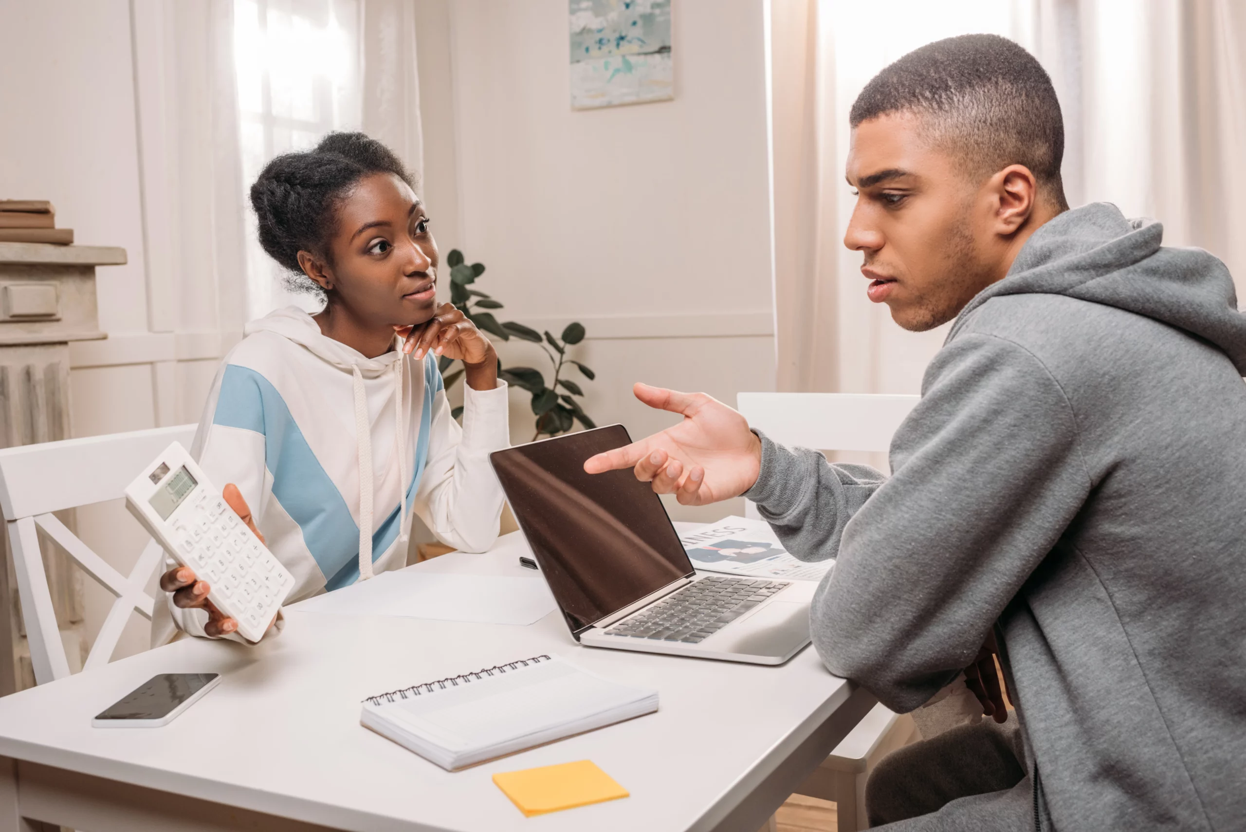 Two people at a table discussing finances with a calculator and laptop, illustrating siblings disagreeing over inheritance issues in California.