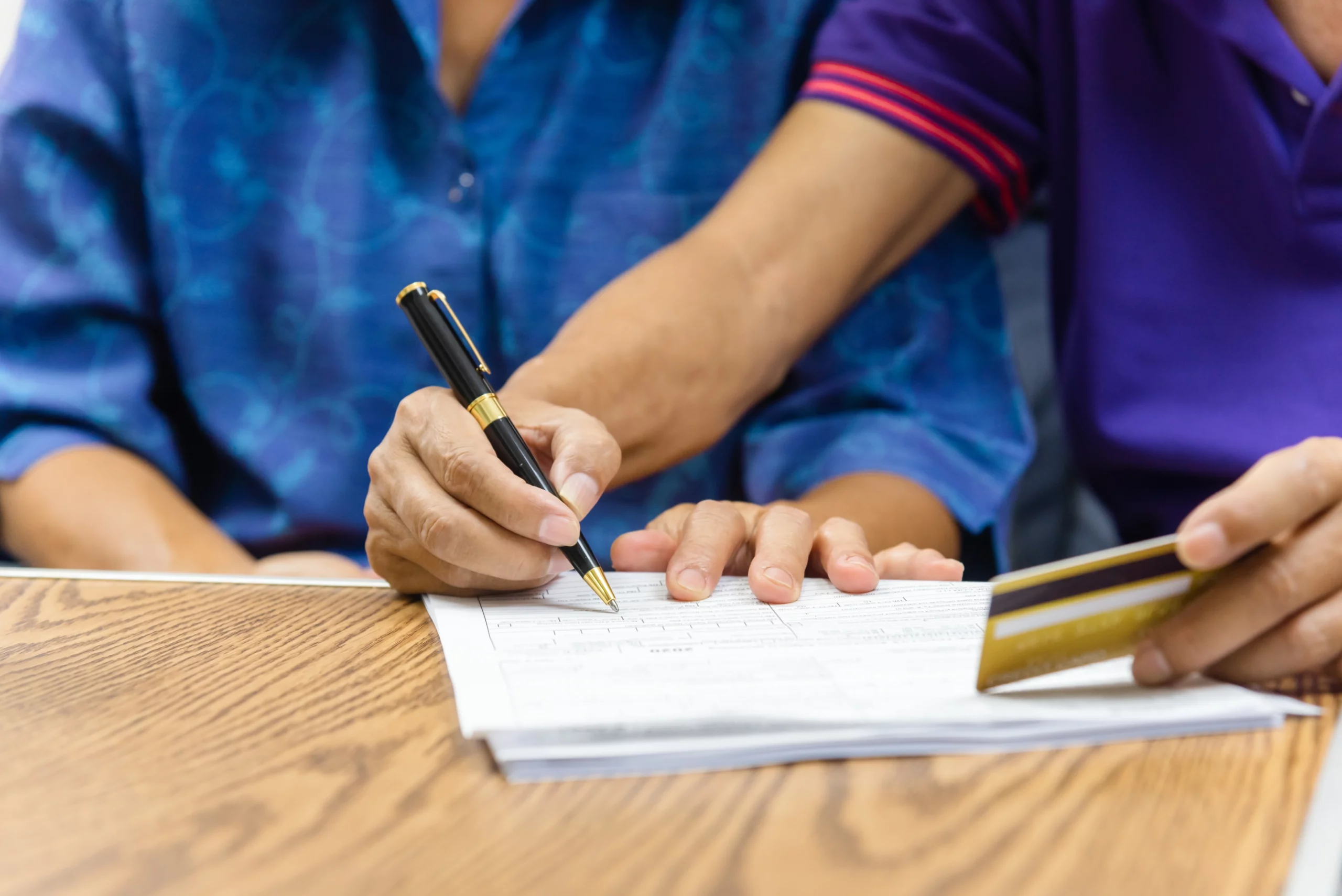 Two people reviewing and signing a document at a table while holding a credit card, illustrating financial decision-making examined in California undue influence cases.