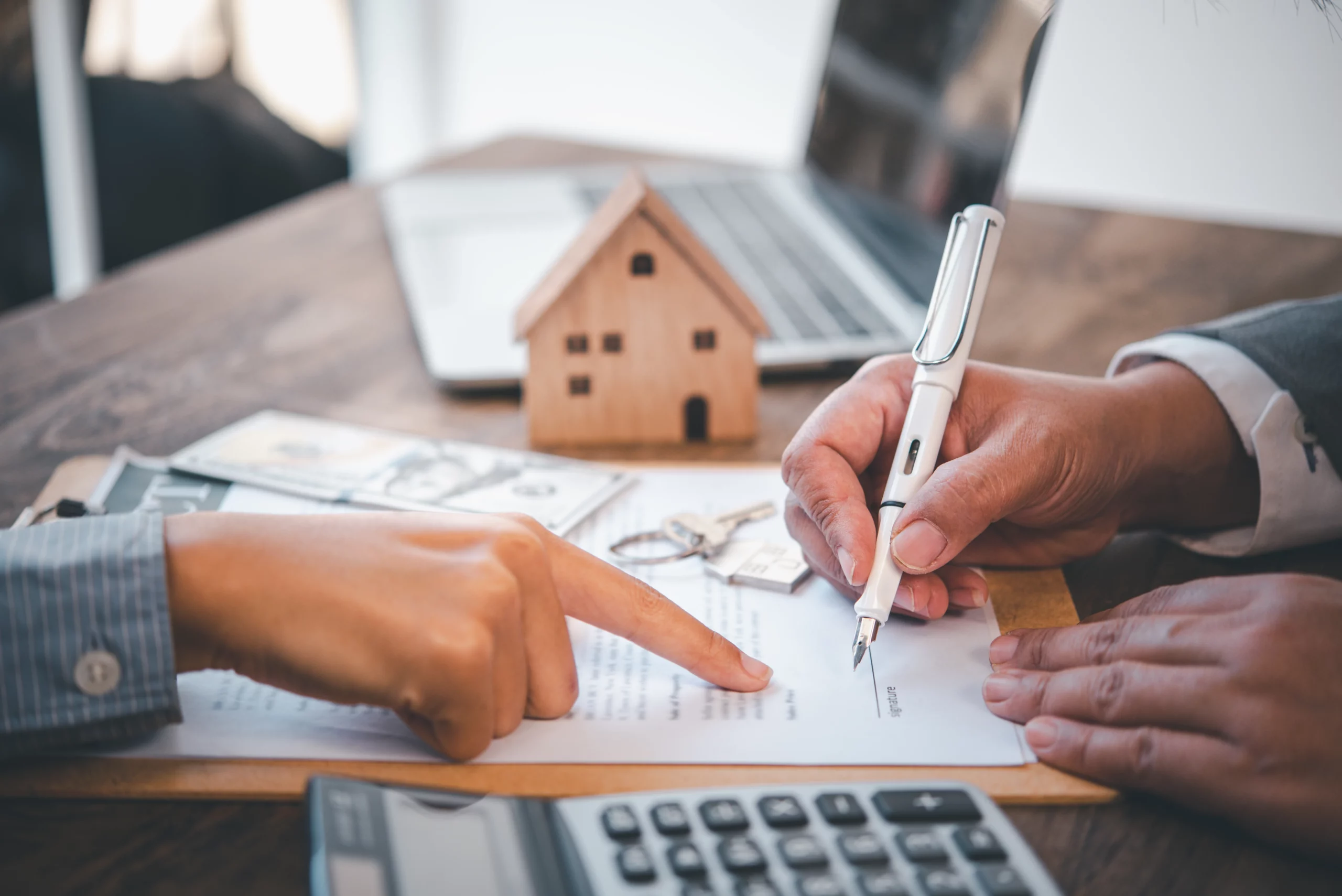 Two professionals in business attire reviewing a document with calculator, house model, and keys, illustrating asset valuation in California probate with a probate referee.