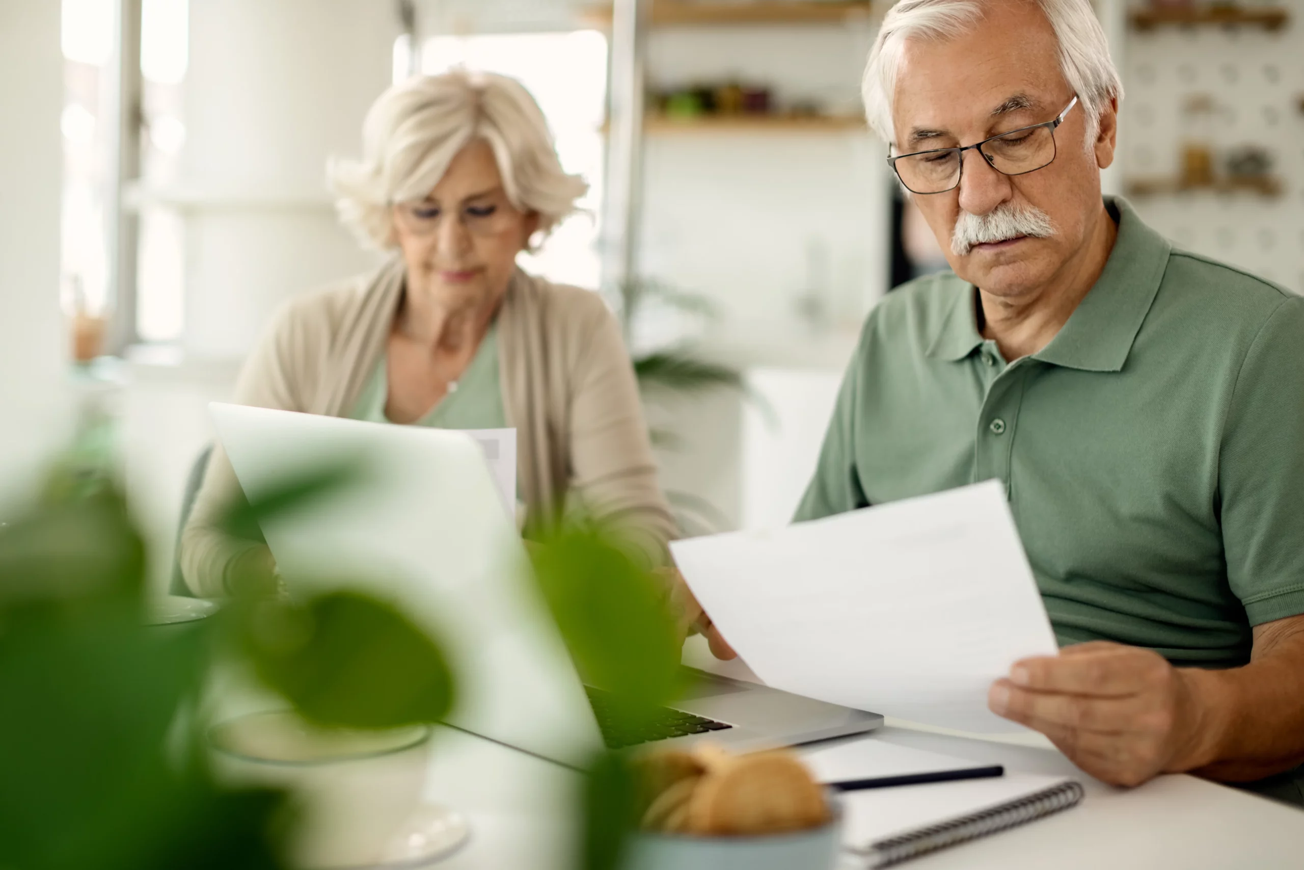 Elderly couple reviewing legal documents and laptop at table, representing concerns about testamentary capacity and the ability to understand and sign a valid will under California law