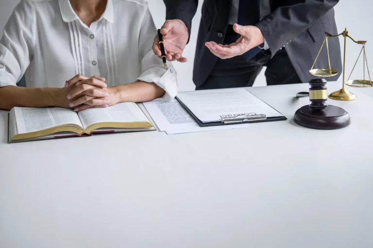 Man and woman reviewing legal documents with a gavel and scales of justice, representing a discussion about trustee misconduct, breach of fiduciary duty, and protecting beneficiary rights under California trust law.