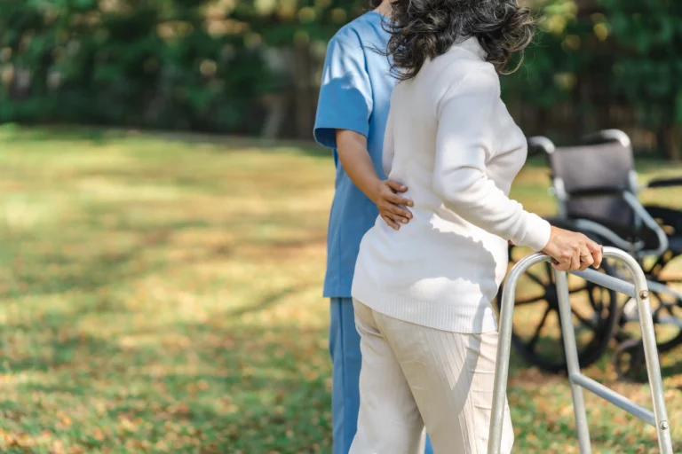 Home 5 Older woman using a walker with caregiver support in California elder care and estate planning
